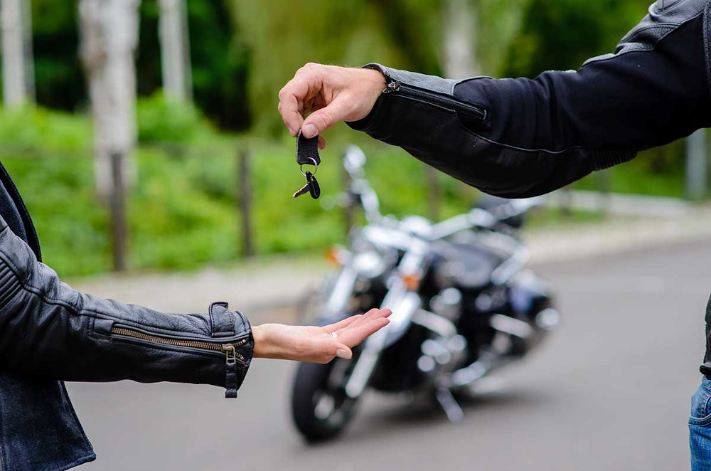 A person giving keys of a bike to another one